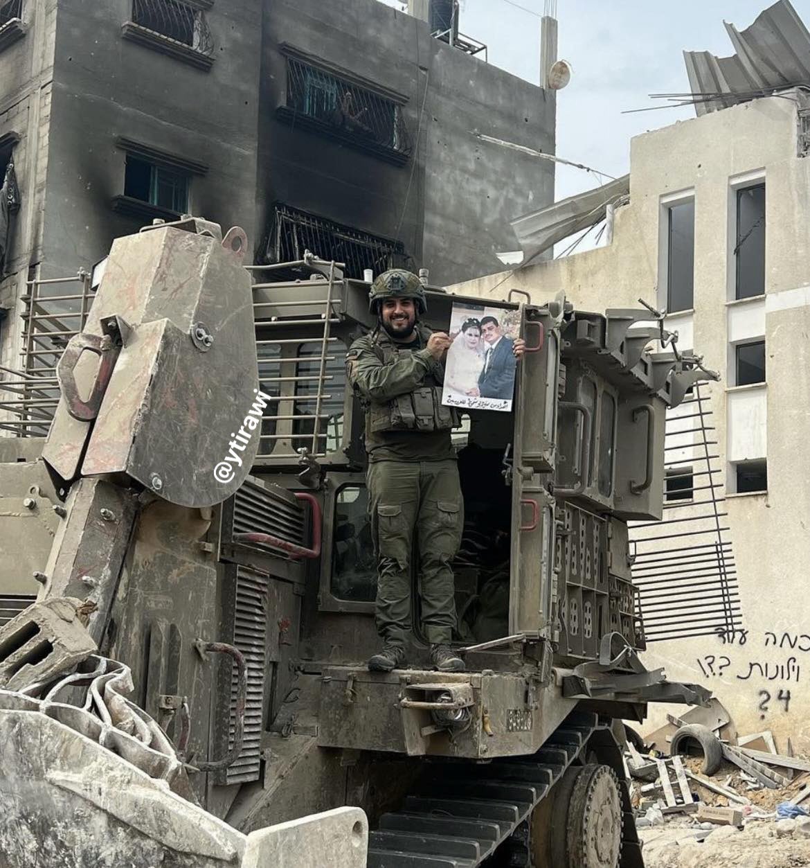 Thumbnail preview image for the video titled: Israeli soldier Dolev Luk, perched on a D9, displaying a Palestinian wedding portrait allegedly looted from a house in Gaza